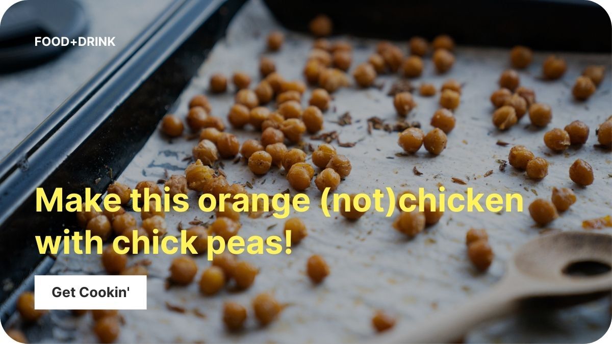 Chickpeas are spread on a flat sheet pan covered with parchment paper. A wooden spoon rests on the pan.