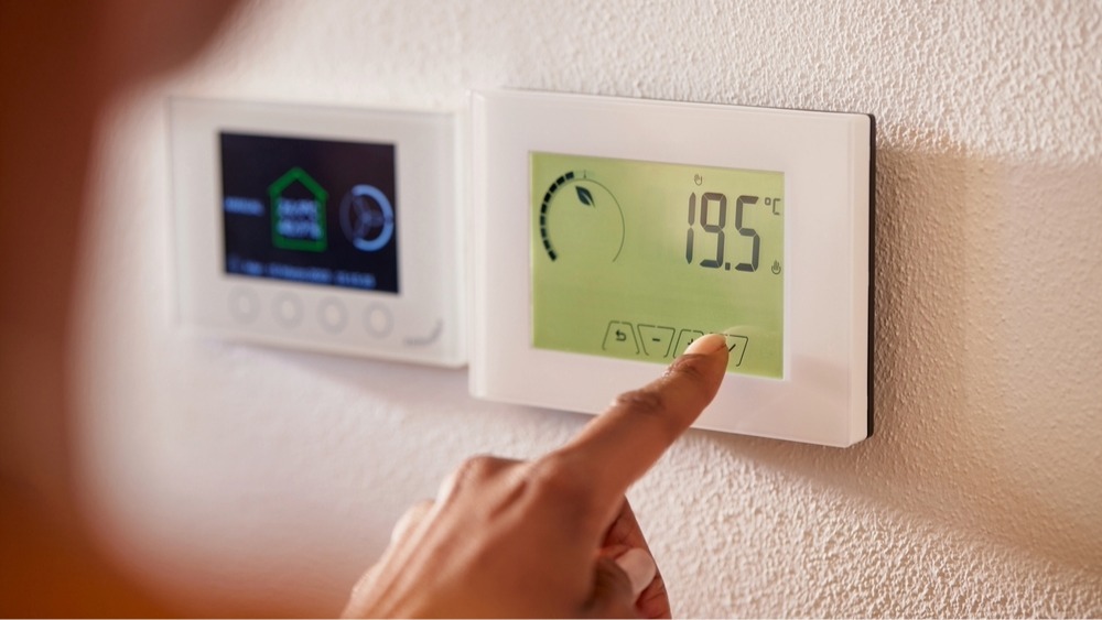 Close-up of someone's hand adjusting a digital thermostat.