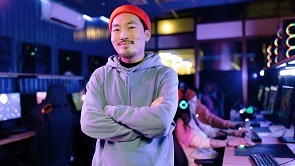 man with hoodie in computer room looking happy