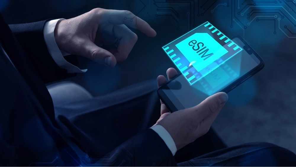 Person wearing a suit they are holding an smartphone in their had and there is a hologram of esim hovering above the screen.