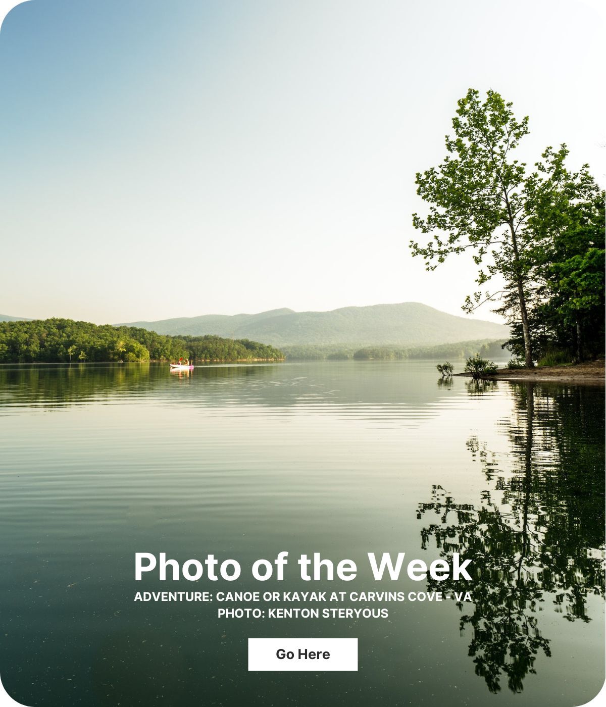 A glass-smooth lake reflects the mountains in the distance.