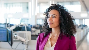 A black professional woman walking through a large open area with computers