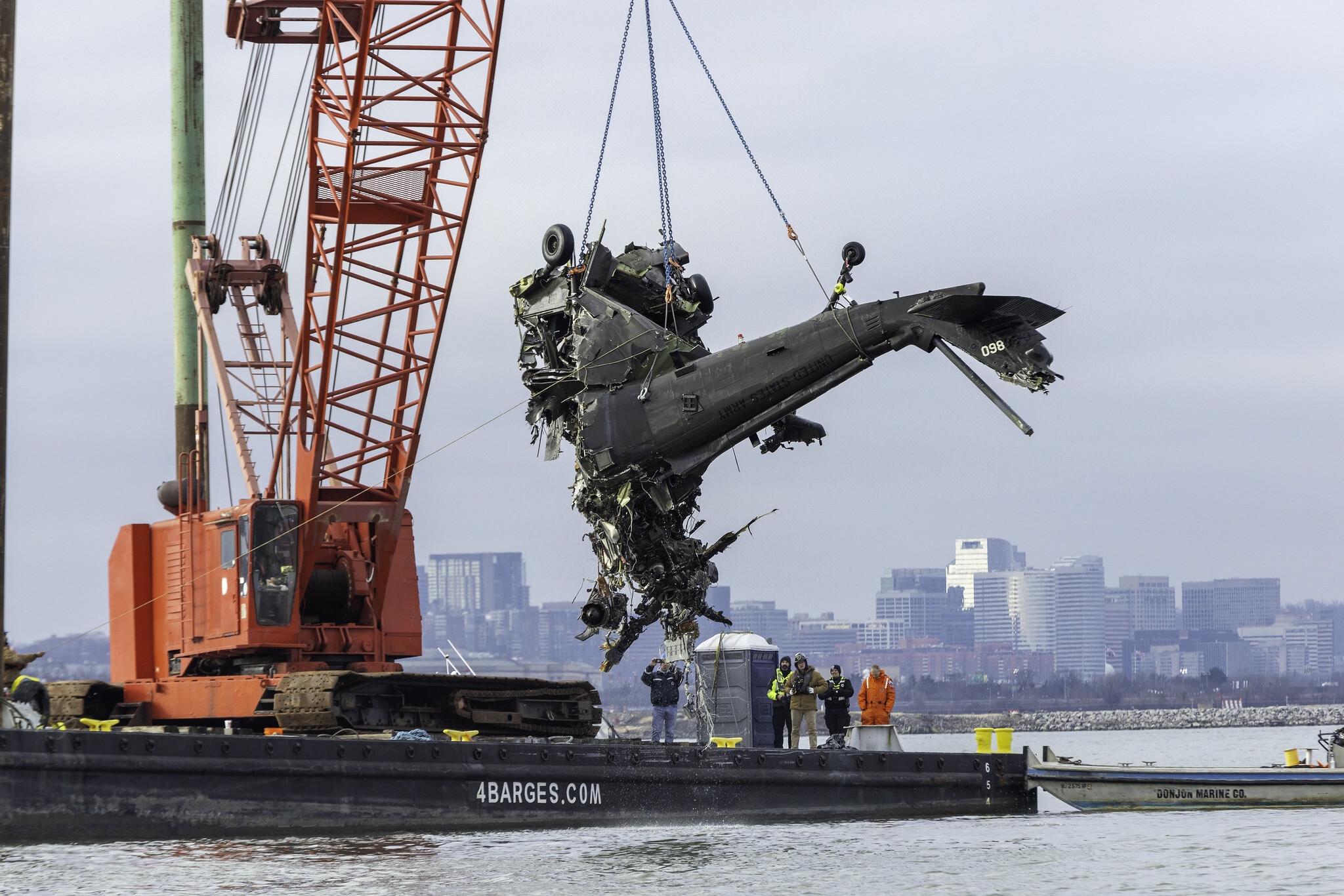 Wreckage of the UH-60L Black Hawk helicopter is lifted on to a barge in the Potomac River.