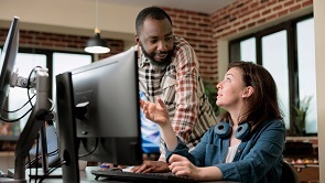 Man speaking to woman, looking over her shoulder at computer monitor