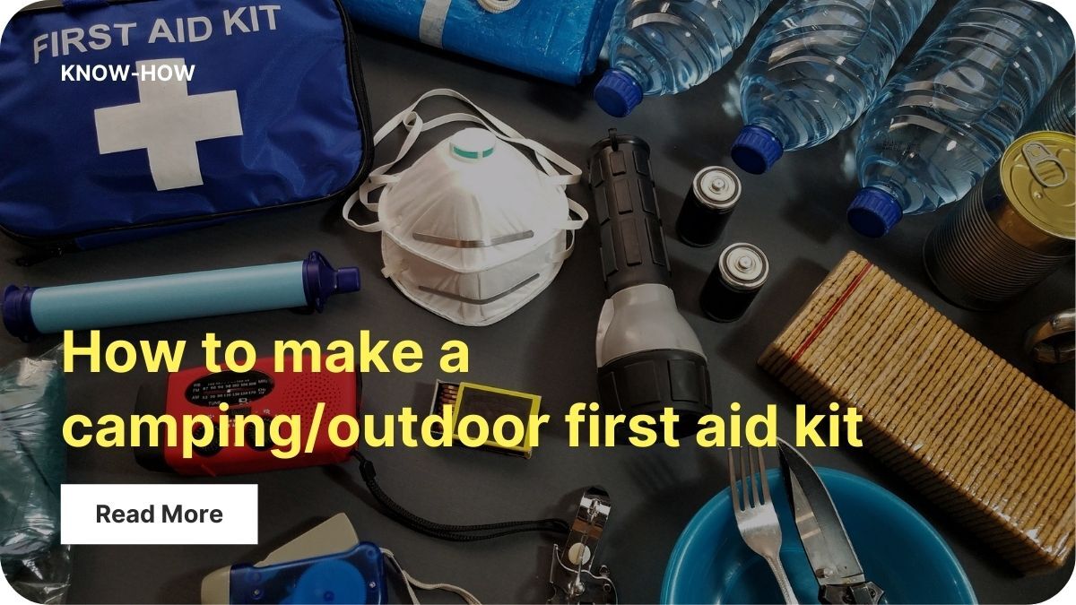 A from-above view of first aid items laid out on a dark surface, including masks, a flashlight, matches, batteries, bottled water, a knife, fork, and bowl.